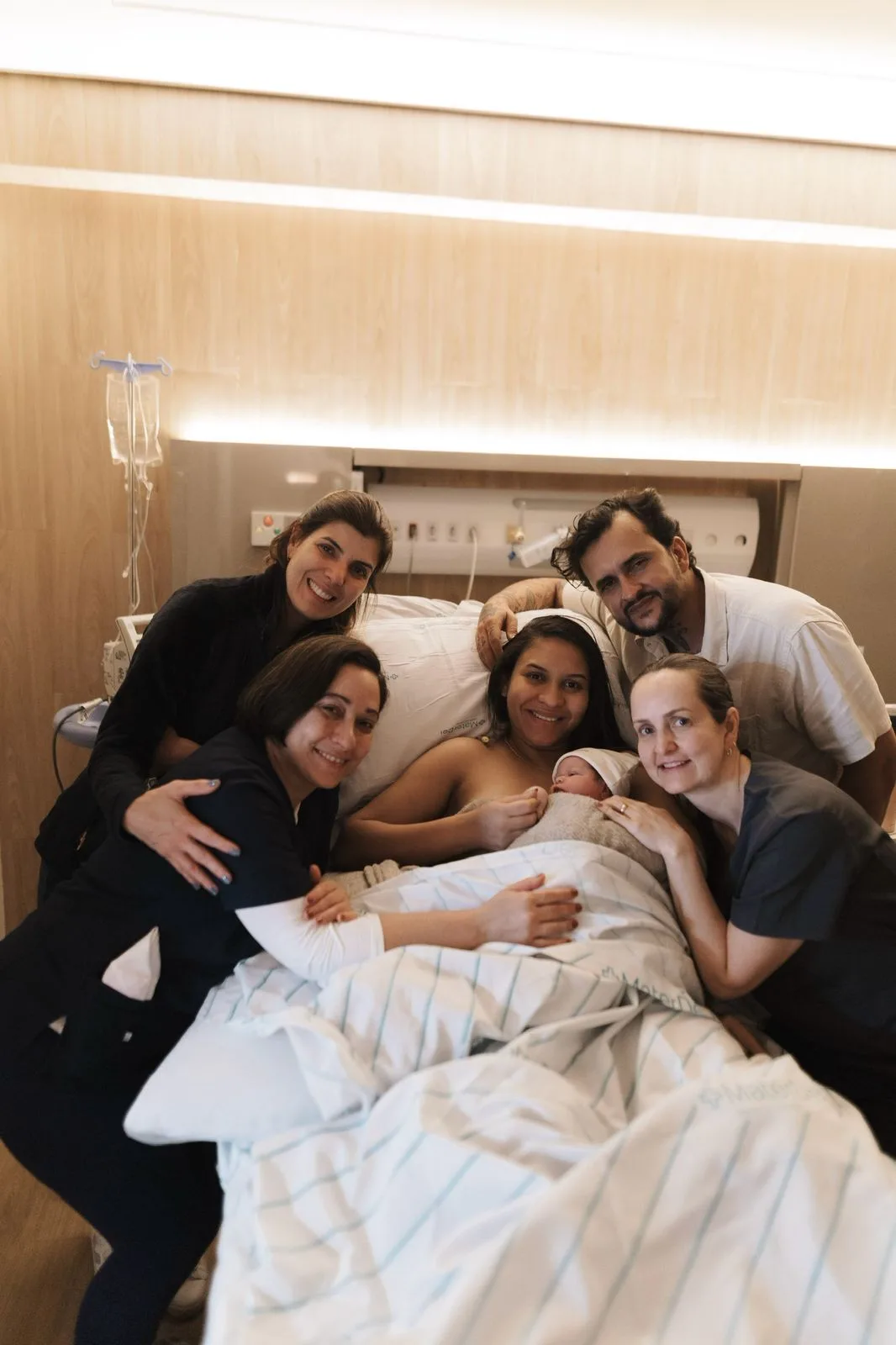 Família reunida com o recém-nascido no quarto da maternidade