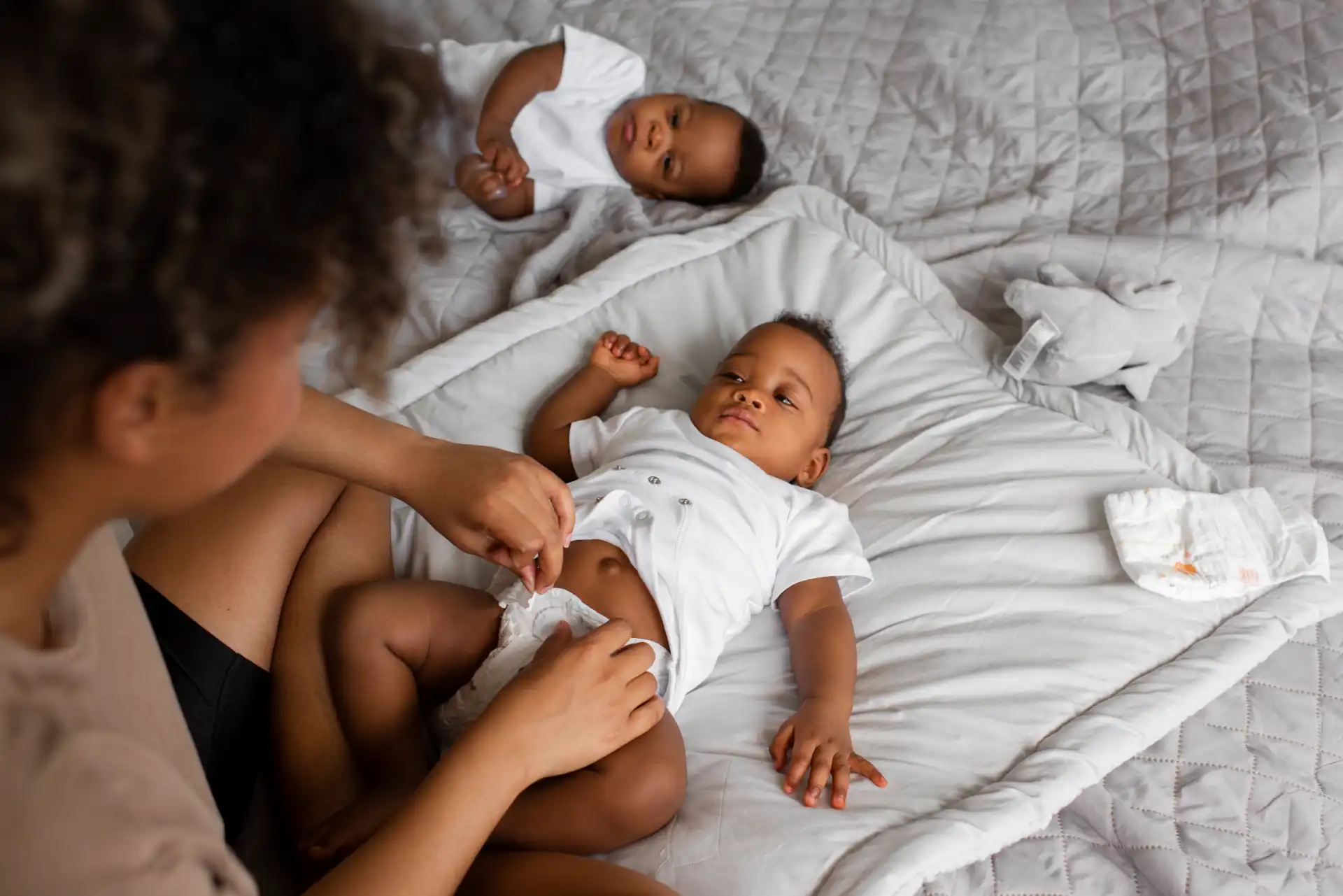 Recuperação pós-parto: mãe trocando fralda de bebê recém-nascido em casa.