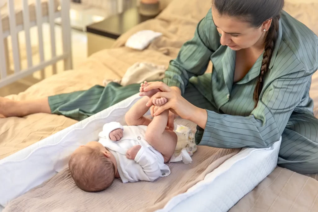Mãe interagindo com o bebê na cama, destacando a importância da recuperação pós-parto e do vínculo afetivo após o nascimento.