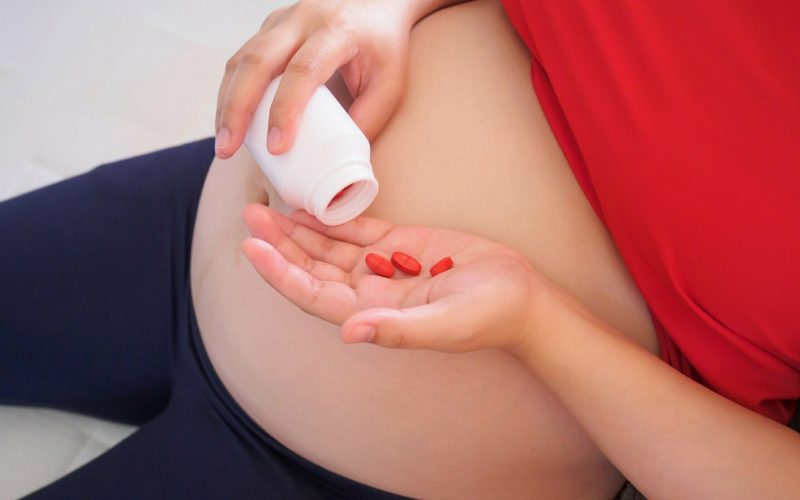 pregnant woman with vitamin pills on her hand